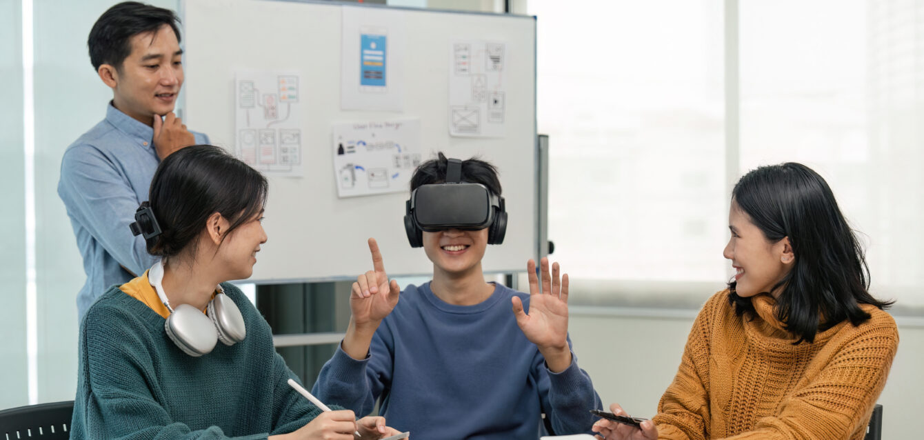 Diverse development team testing virtual reality headset, brainstorming on augmented reality improvement, future technology