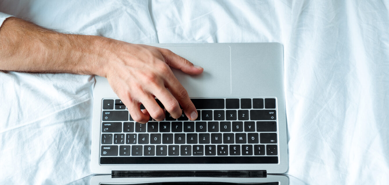 top view of man typing on laptop keyboard, illustrative editorial