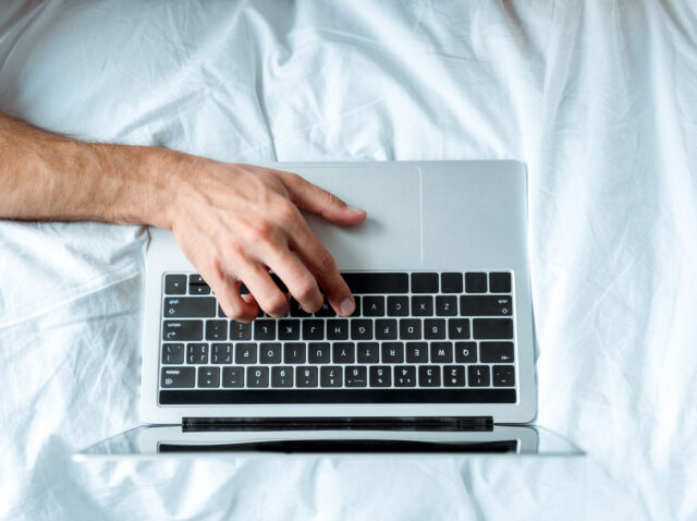 top view of man typing on laptop keyboard, illustrative editorial