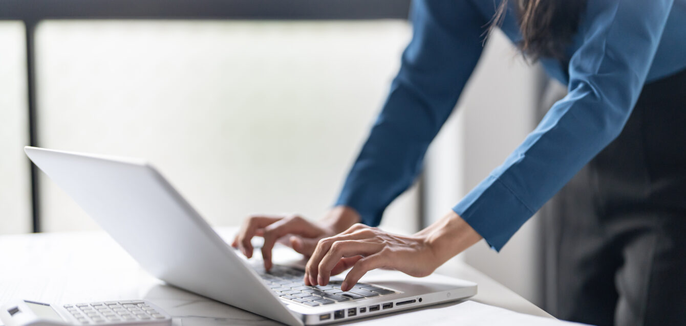 Working by using a laptop computer on wooden table. Hands typing